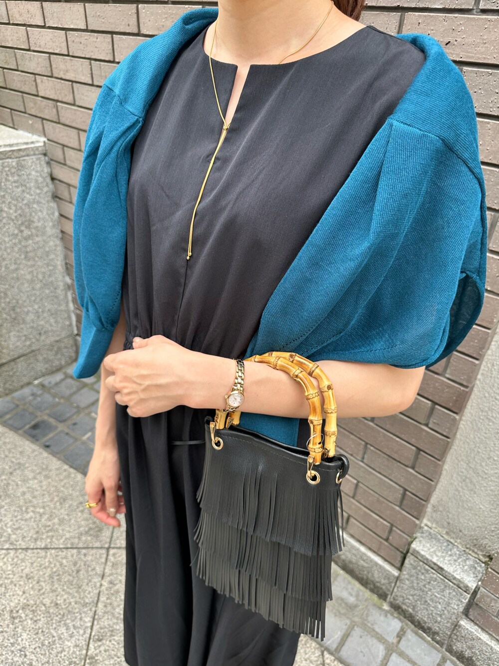 ゴールド系のハンドバッグ、ゴールド系のサンダル、ブルー系のワンピースを着用したレディースの夏コーディネートの2枚目の写真