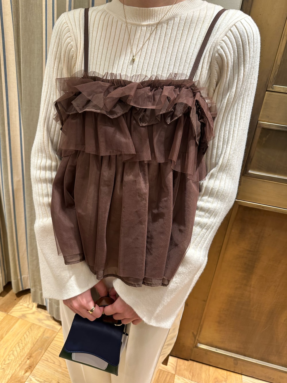 ホワイト系のニット/セーター、ブラウン系のシャツ/ブラウス、ブラック系のブーツを着用したレディースの冬コーディネートの3枚目の写真