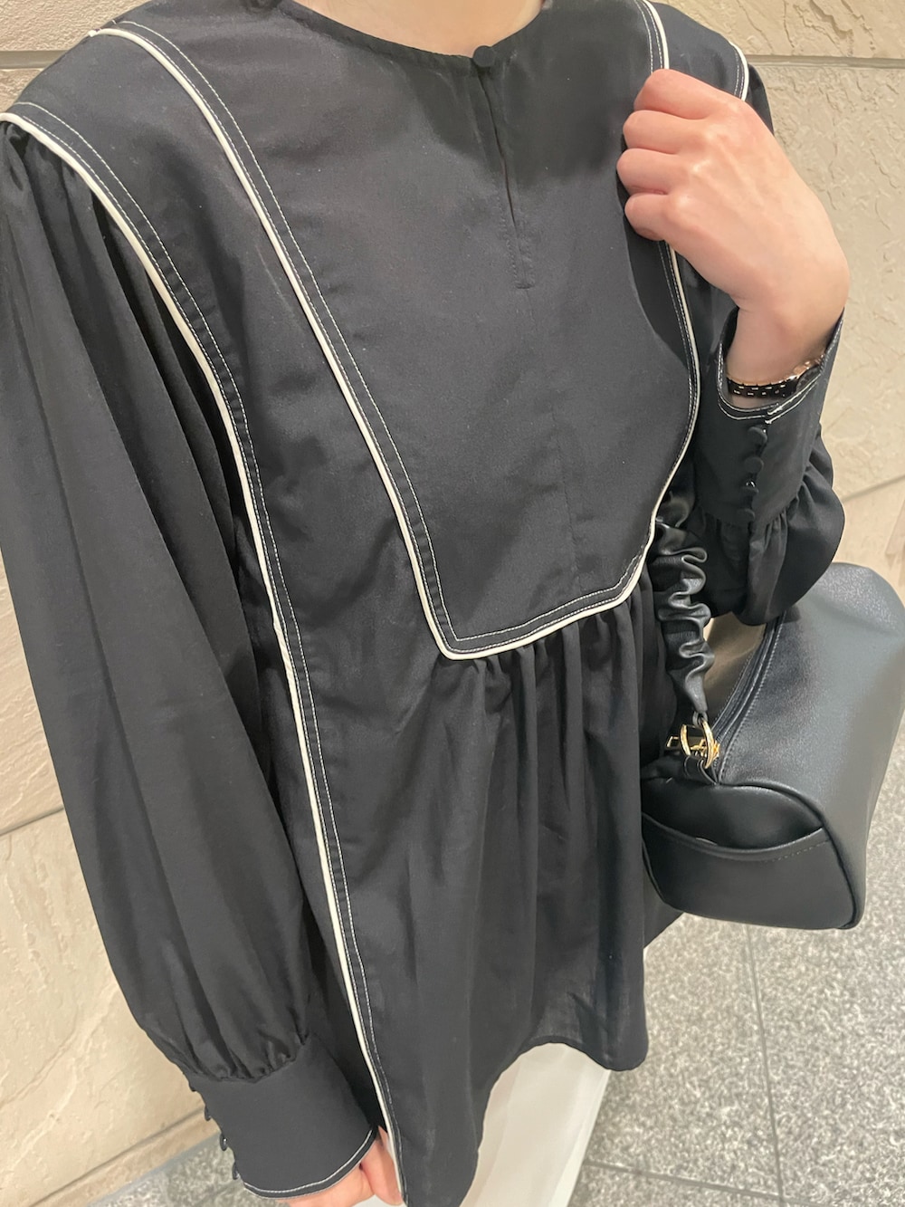 ブラック系のシャツ/ブラウス、ブラック系のハンドバッグ、ゴールド系のパンプスを着用したレディースの春コーディネートの2枚目の写真