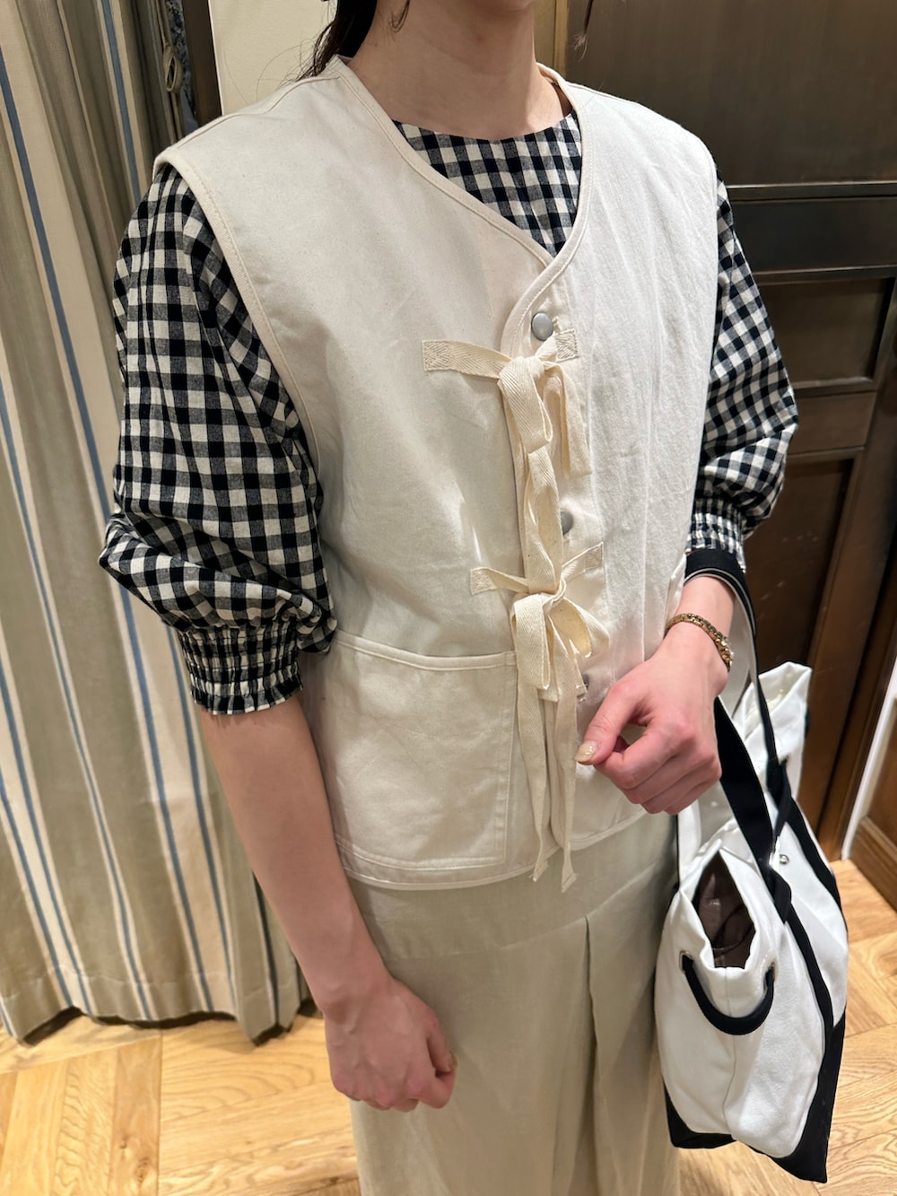 ホワイト系のシャツ/ブラウス、ホワイト系のベスト、ブラック系のハンドバッグを着用したレディースの春コーディネートの4枚目の写真