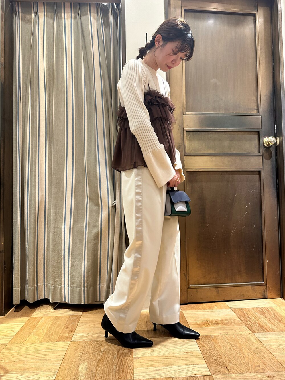 ホワイト系のニット/セーター、ブラウン系のシャツ/ブラウス、ブラック系のブーツを着用したレディースの冬コーディネートの2枚目の写真