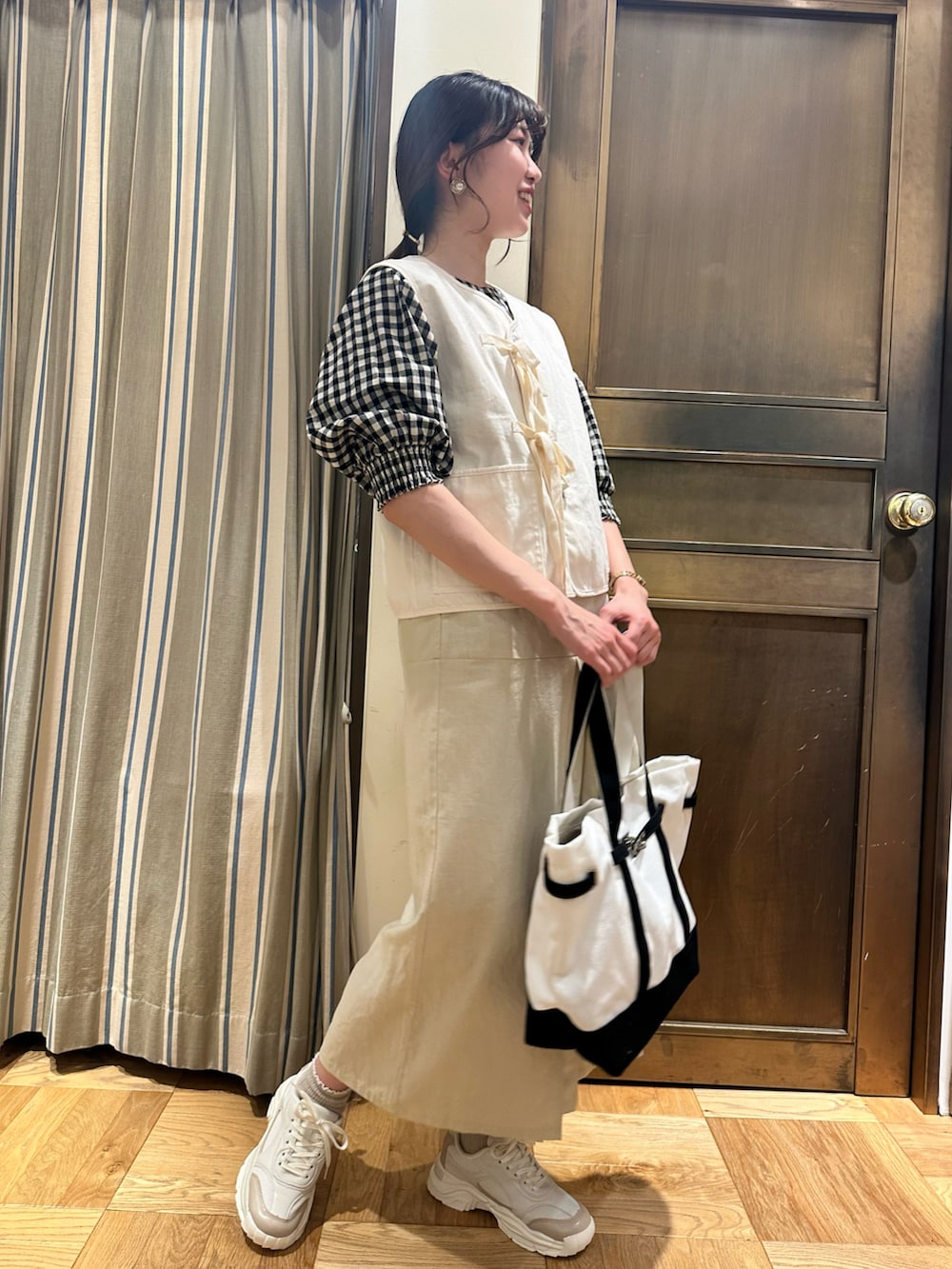 ホワイト系のシャツ/ブラウス、ホワイト系のベスト、ブラック系のハンドバッグを着用したレディースの春コーディネートの2枚目の写真