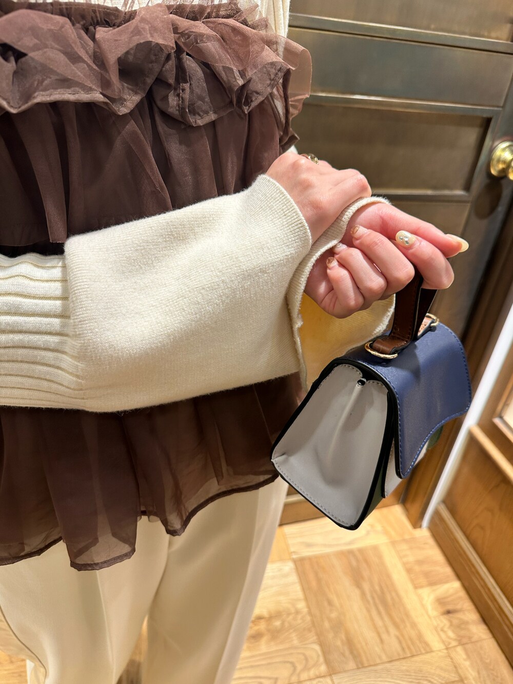 ホワイト系のニット/セーター、ブラウン系のシャツ/ブラウス、ブラック系のブーツを着用したレディースの冬コーディネートの4枚目の写真