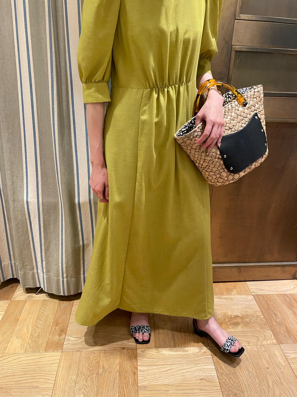 イエロー系のワンピース、ブラック系のハンドバッグを着用したレディースの春コーディネートの3枚目の写真