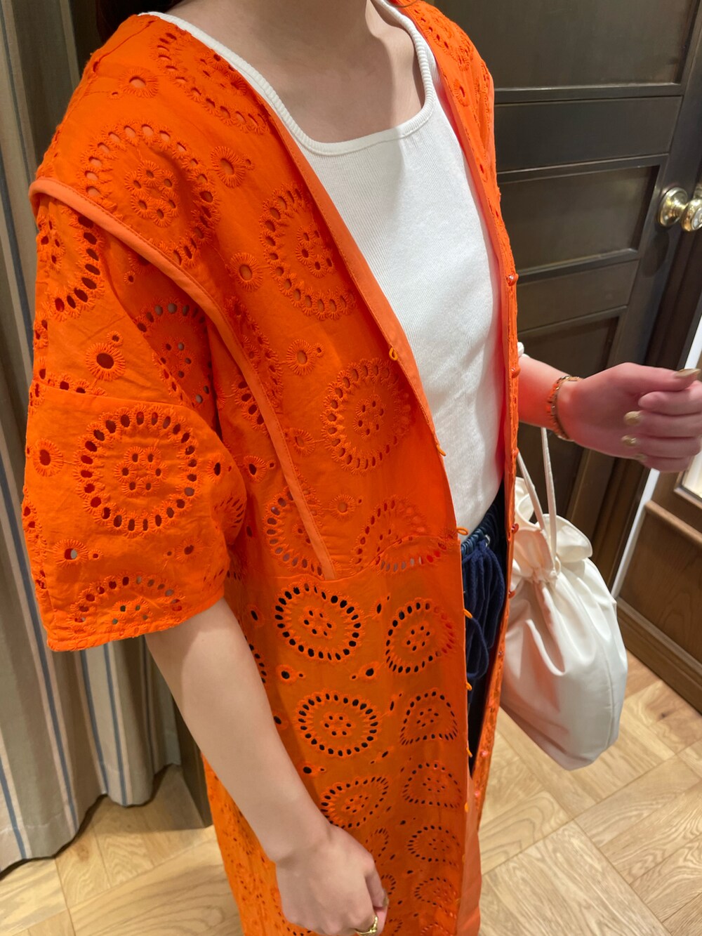 オレンジ系のワンピース、ホワイト系のタンクトップ、ブルー系のデニムパンツを着用したレディースの春コーディネートの3枚目の写真