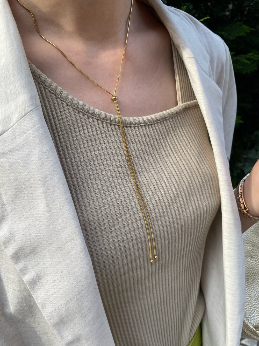 ベージュ系のタンクトップ、ホワイト系のノーカラージャケット、イエロー系のその他パンツを着用したレディースの春コーディネートの2枚目の写真