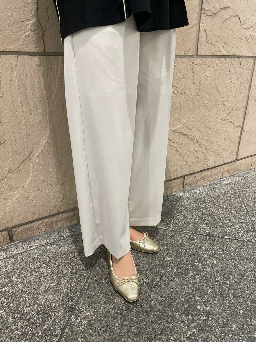 ブラック系のシャツ/ブラウス、ブラック系のハンドバッグ、ゴールド系のパンプスを着用したレディースの春コーディネートの3枚目の写真