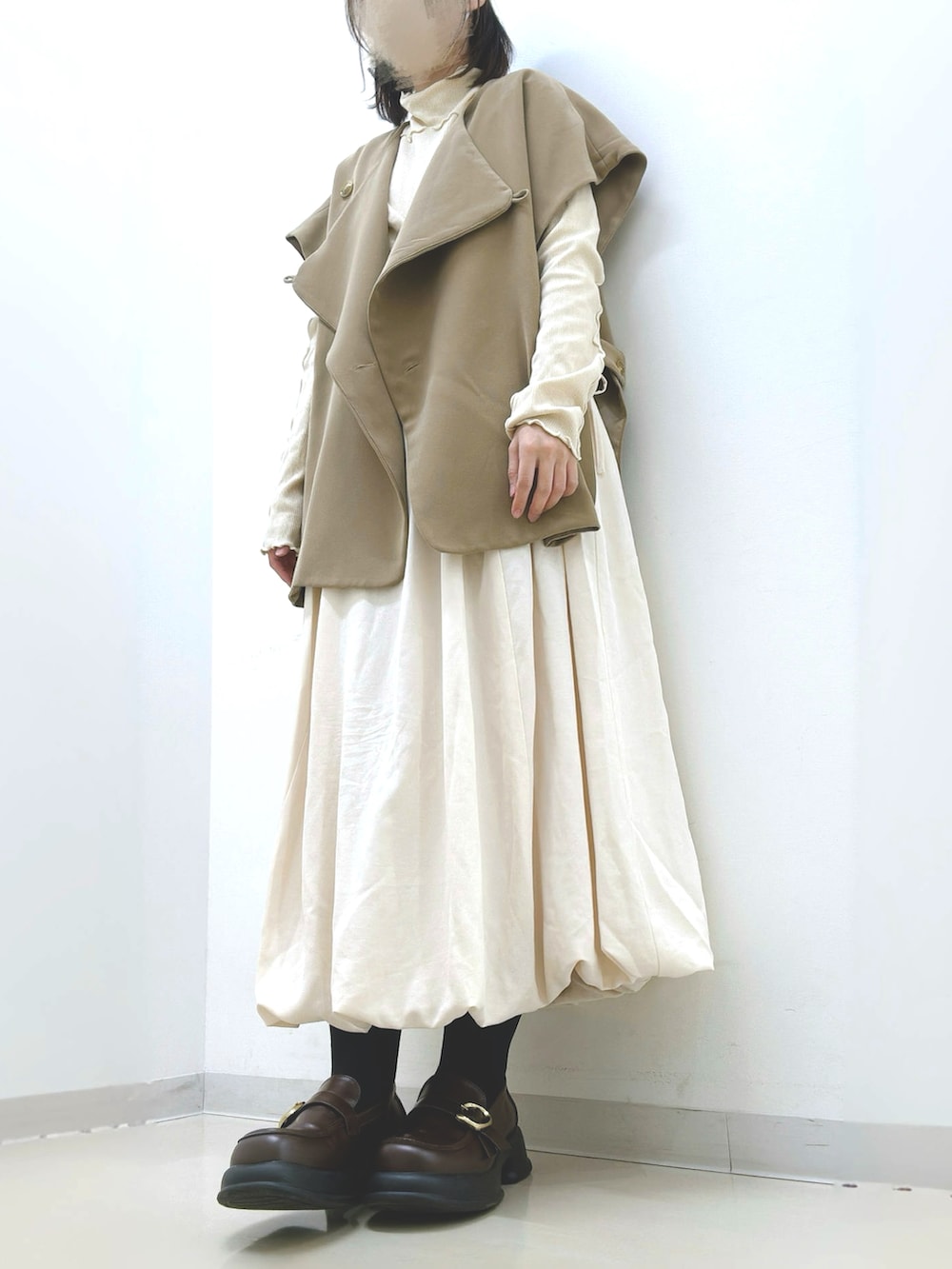 ベージュ系のダウンジャケット/コート、ベージュ系のベスト、ベージュ系のスカートを着用したレディースの秋コーディネートの2枚目の写真