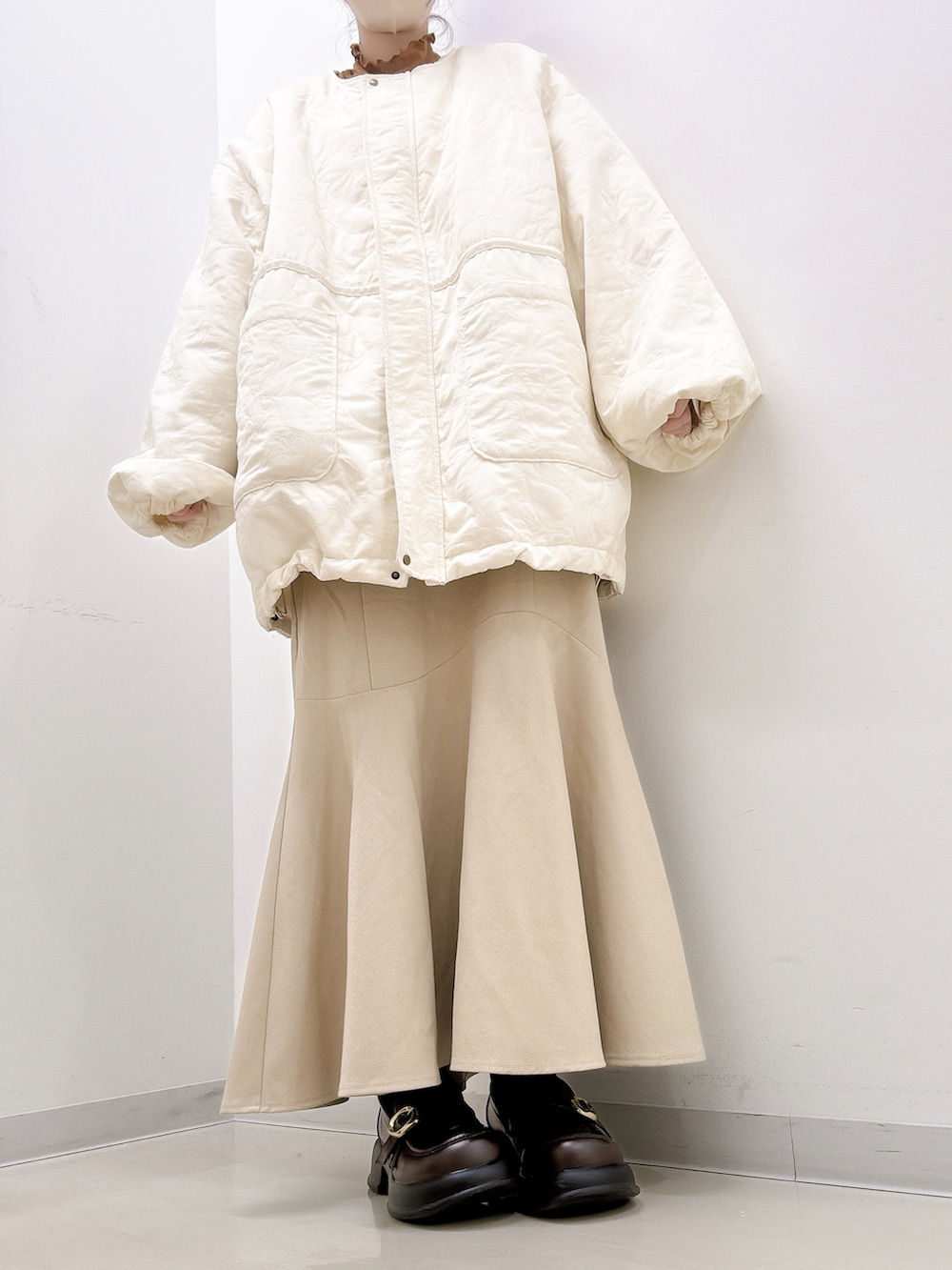 ベージュ系のブルゾン、ブラウン系のTシャツ/カットソー、ベージュ系のスカートを着用したレディースの秋コーディネートの2枚目の写真