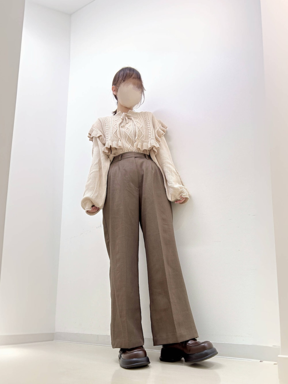 ブラウン系のスラックス、ブラウン系のローファー、ベージュ系のニット/セーターを着用したレディースの秋コーディネートの2枚目の写真