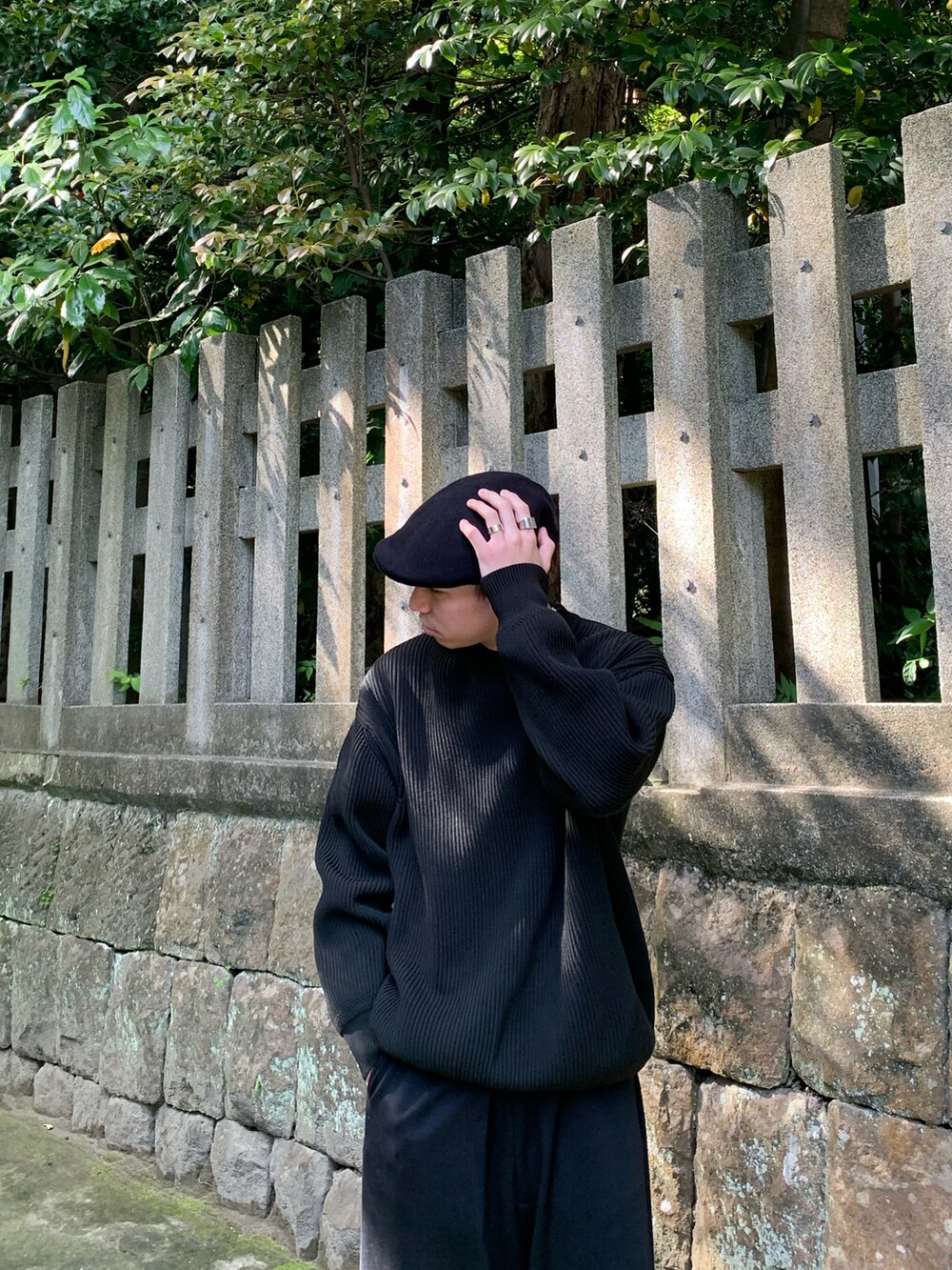 ブラック系のニット/セーター、ブラック系のパンツ、ホワイト系のスニーカーを着用したメンズの夏コーディネートの2枚目の写真