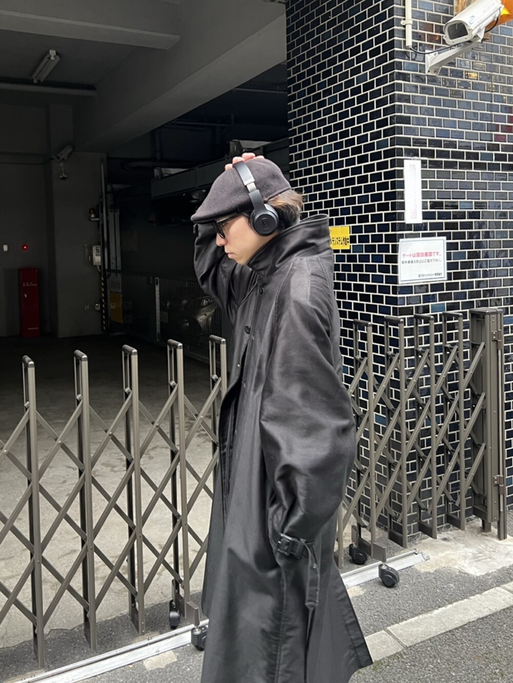 ブラック系のステンカラーコート、グレー系のスラックス、ブラック系のサンダルを着用したメンズの冬コーディネートの3枚目の写真