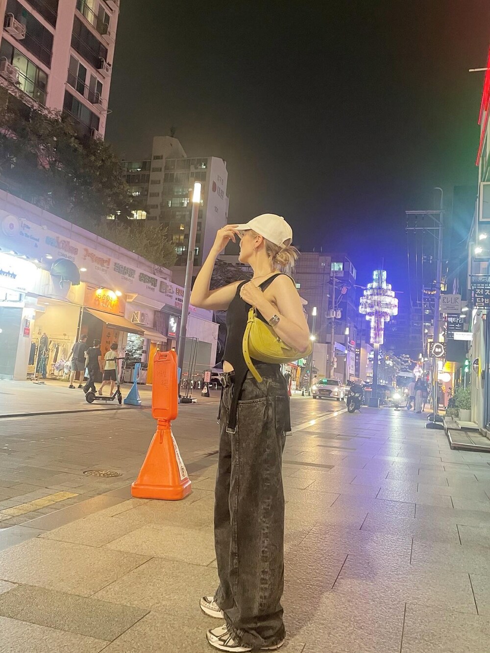 ブラック系のデニムパンツ、ブラック系のタンクトップ、シルバー系のスニーカーを着用したレディースの秋コーディネートの2枚目の写真