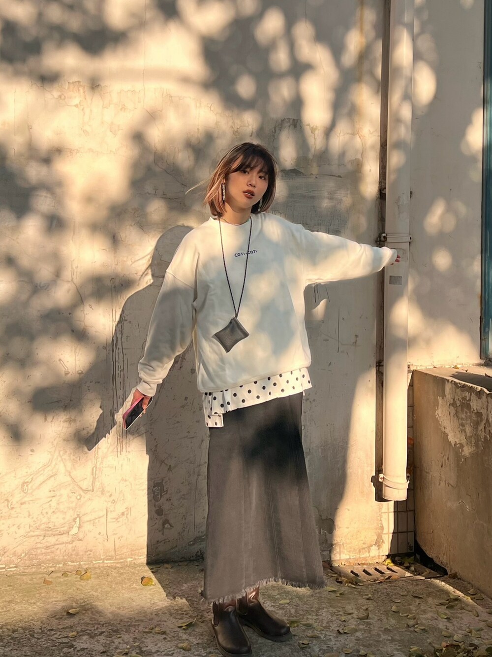 ブラック系のジャンパースカート、ブラウン系のブーツ、ホワイト系のTシャツ/カットソーを着用したレディースの春コーディネートの2枚目の写真