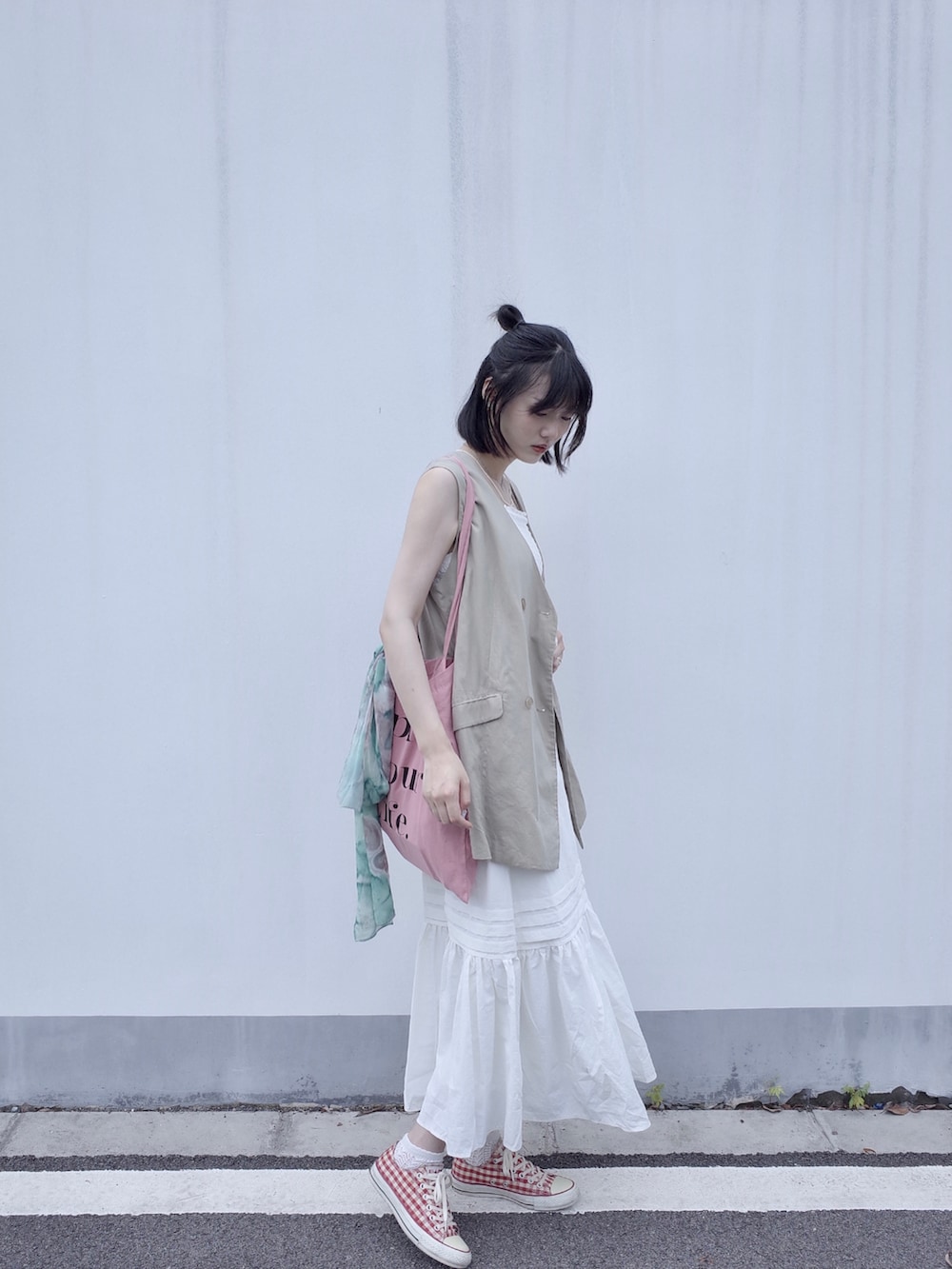 ベージュ系のベスト、ホワイト系のスカート、レッド系のスニーカーを着用したレディースの夏コーディネートの3枚目の写真