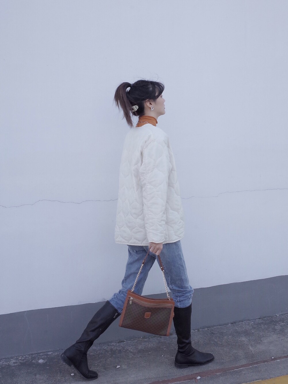 ブルー系のデニムパンツ、ホワイト系のブルゾン、オレンジ系のTシャツ/カットソーを着用したレディースの冬コーディネートの3枚目の写真