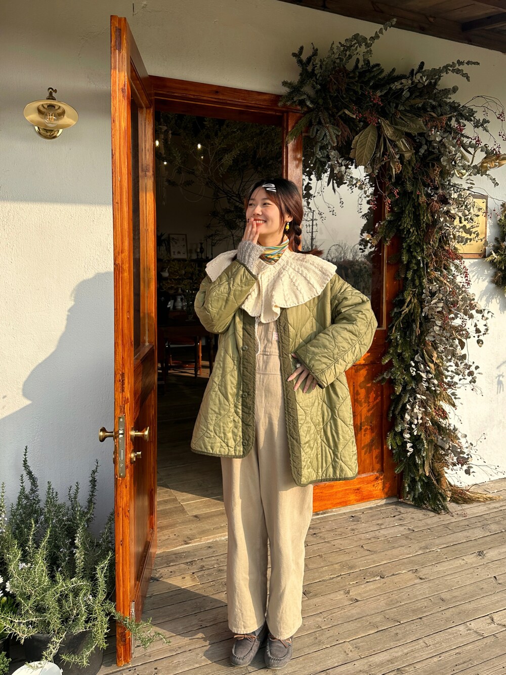 グリーン系のミリタリージャケット、イエロー系のTシャツ/カットソー、ホワイト系のニット/セーターを着用したレディースの冬コーディネートの2枚目の写真