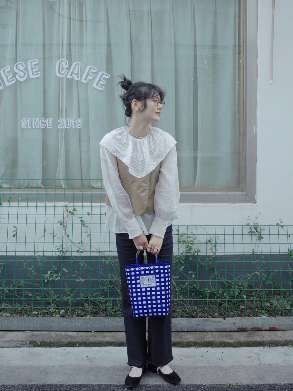 ベージュ系のベスト、ホワイト系のシャツ/ブラウス、ブルー系のデニムパンツを着用したレディースの春コーディネートの2枚目の写真