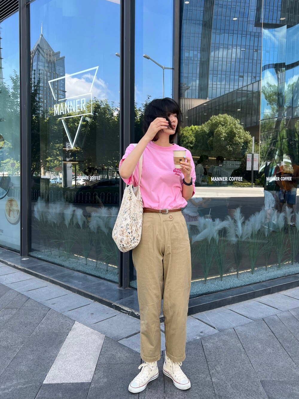 ホワイト系のスニーカー、ベージュ系のバッグ、ピンク系のTシャツ/カットソーを着用したレディースの夏コーディネートの3枚目の写真