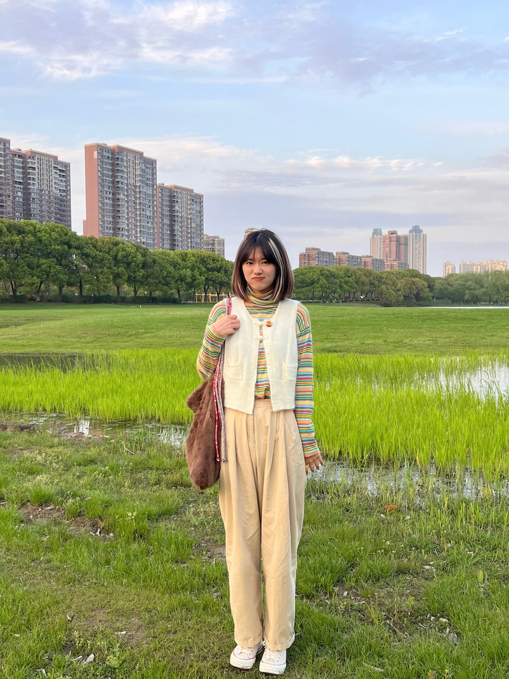 ホワイト系のベスト、イエロー系のTシャツ/カットソー、ホワイト系のスニーカーを着用したレディースの春コーディネートの3枚目の写真