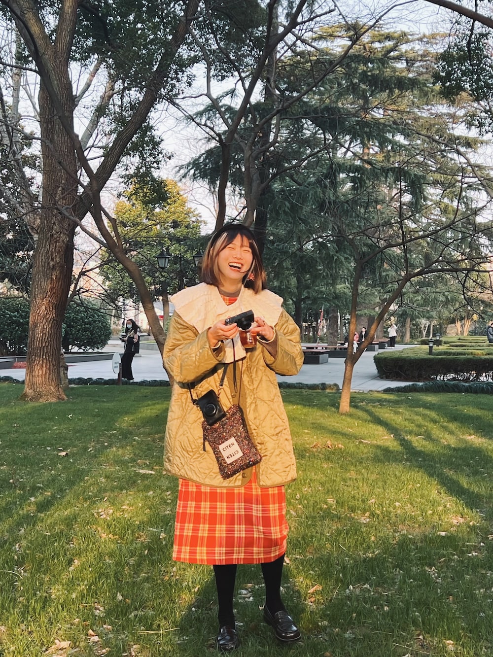 グリーン系のミリタリージャケット、その他のショルダーバッグ、レッド系のワンピースを着用したレディースの春コーディネートの3枚目の写真