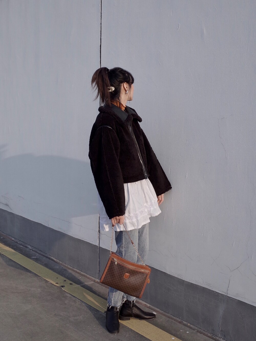 ブラック系のムートンコート、ブルー系のデニムパンツ、ホワイト系のシャツ/ブラウスを着用したレディースの冬コーディネートの2枚目の写真