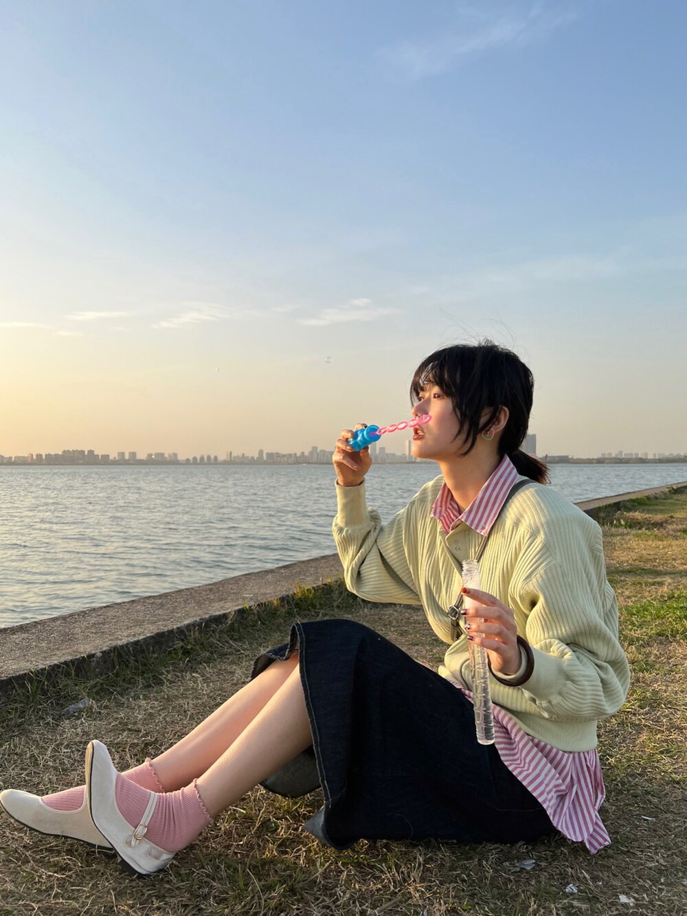 グリーン系のカーディガン/ボレロ、ブルー系のデニムスカート、ピンク系のシャツ/ブラウスを着用したレディースの春コーディネートの2枚目の写真