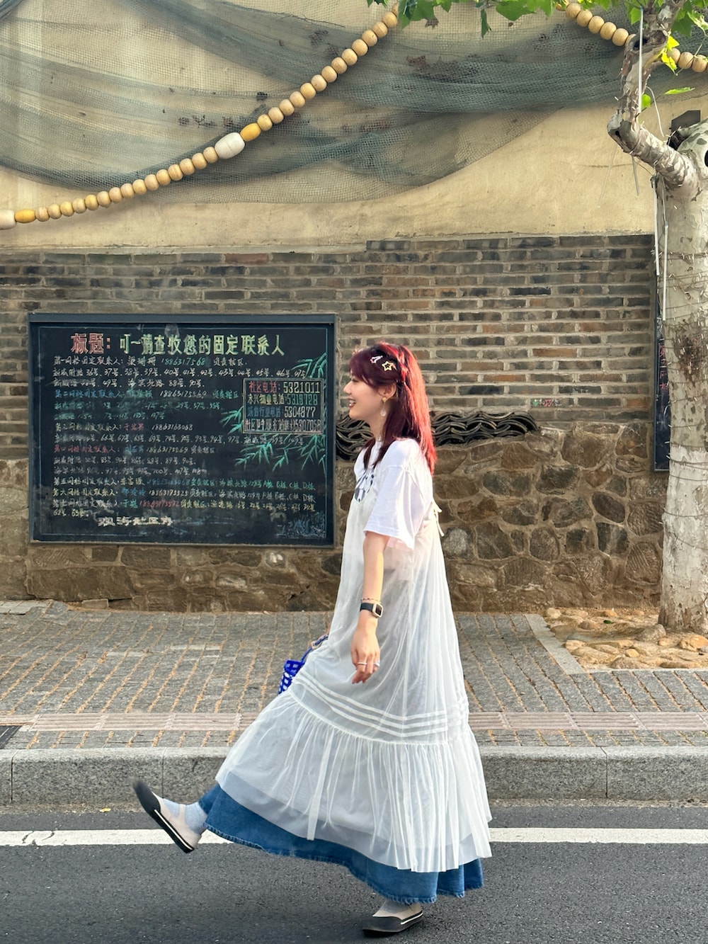 ホワイト系のワンピース、ブルー系のバッグ、ブルー系のデニムスカートを着用したレディースの夏コーディネートの2枚目の写真