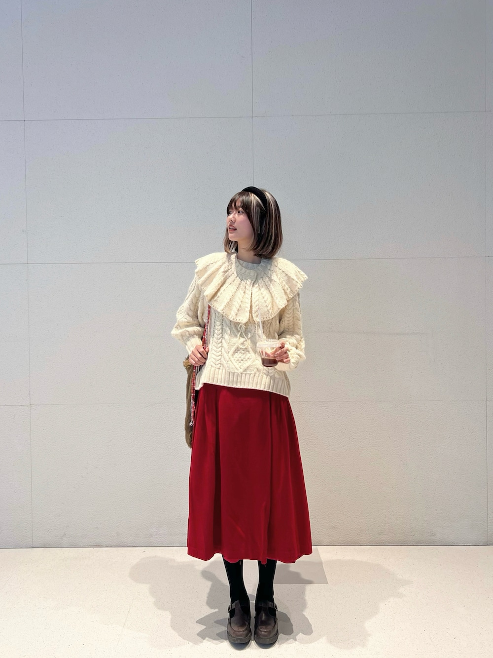 ホワイト系のニット/セーター、ブラウン系のショルダーバッグ、レッド系のスカートを着用したレディースの春コーディネートの3枚目の写真