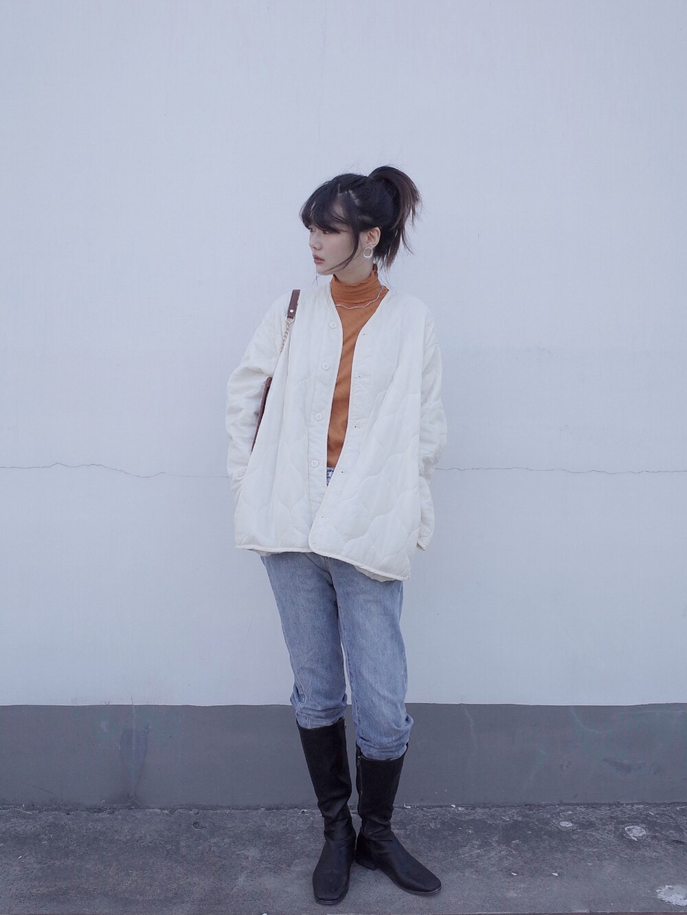 ブルー系のデニムパンツ、ホワイト系のブルゾン、オレンジ系のTシャツ/カットソーを着用したレディースの冬コーディネートの2枚目の写真