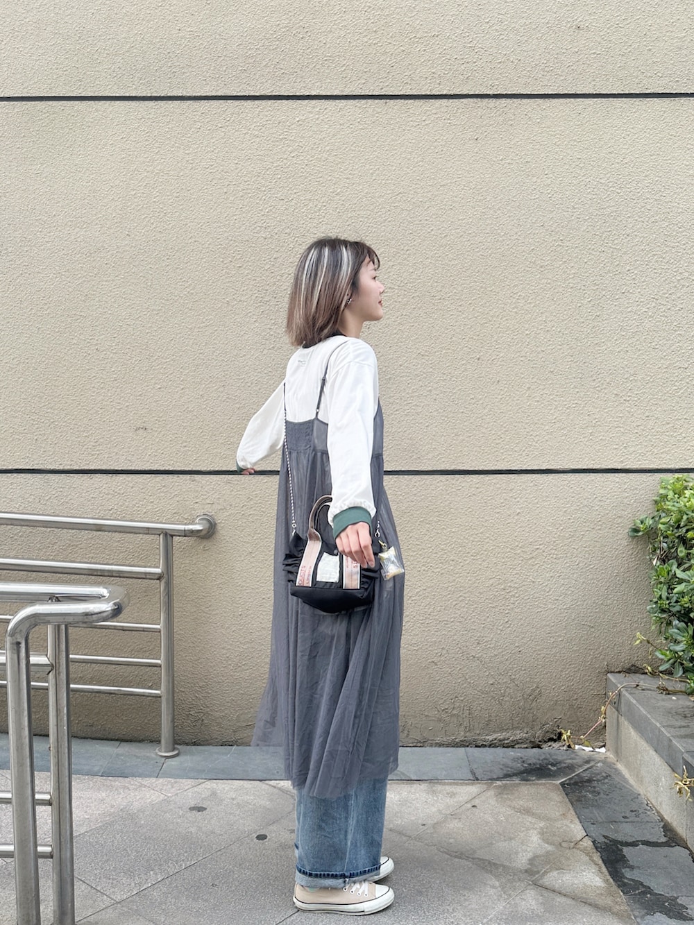 グレー系のワンピース、ベージュ系のTシャツ/カットソー、ブルー系のデニムパンツを着用したレディースの春コーディネートの2枚目の写真