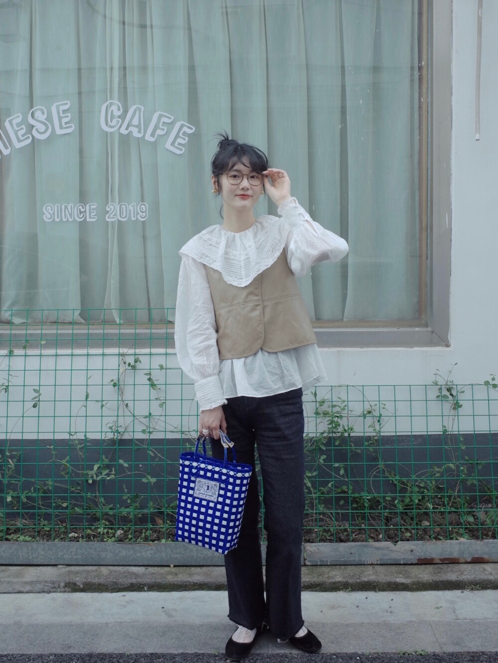 ベージュ系のベスト、ホワイト系のシャツ/ブラウス、ブルー系のデニムパンツを着用したレディースの春コーディネートの3枚目の写真