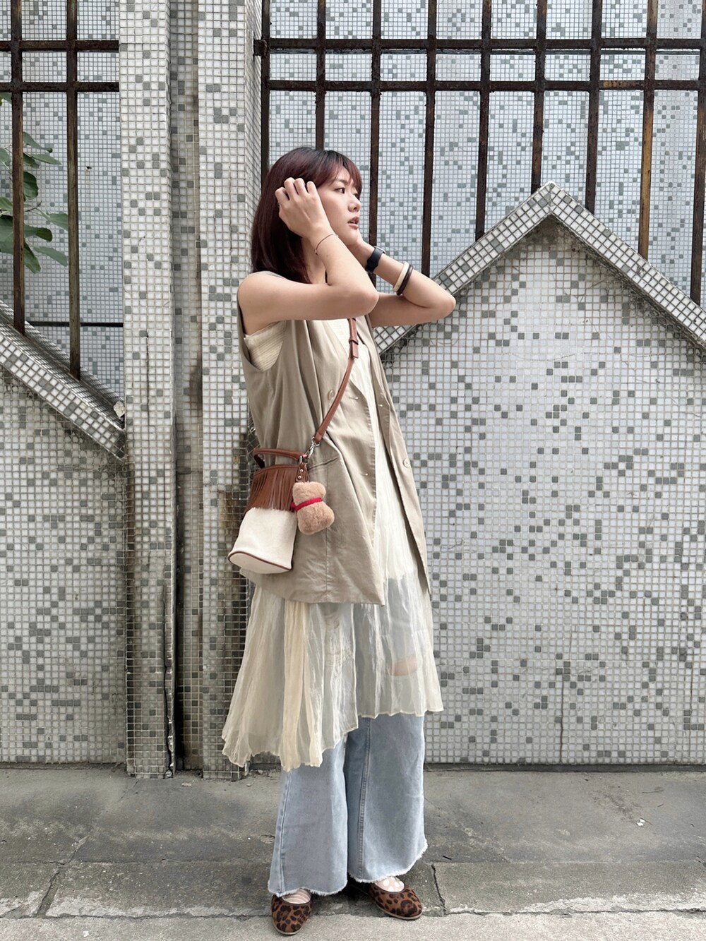 ベージュ系のベスト、ホワイト系のワンピース、ブルー系のデニムパンツを着用したレディースの秋コーディネートの4枚目の写真