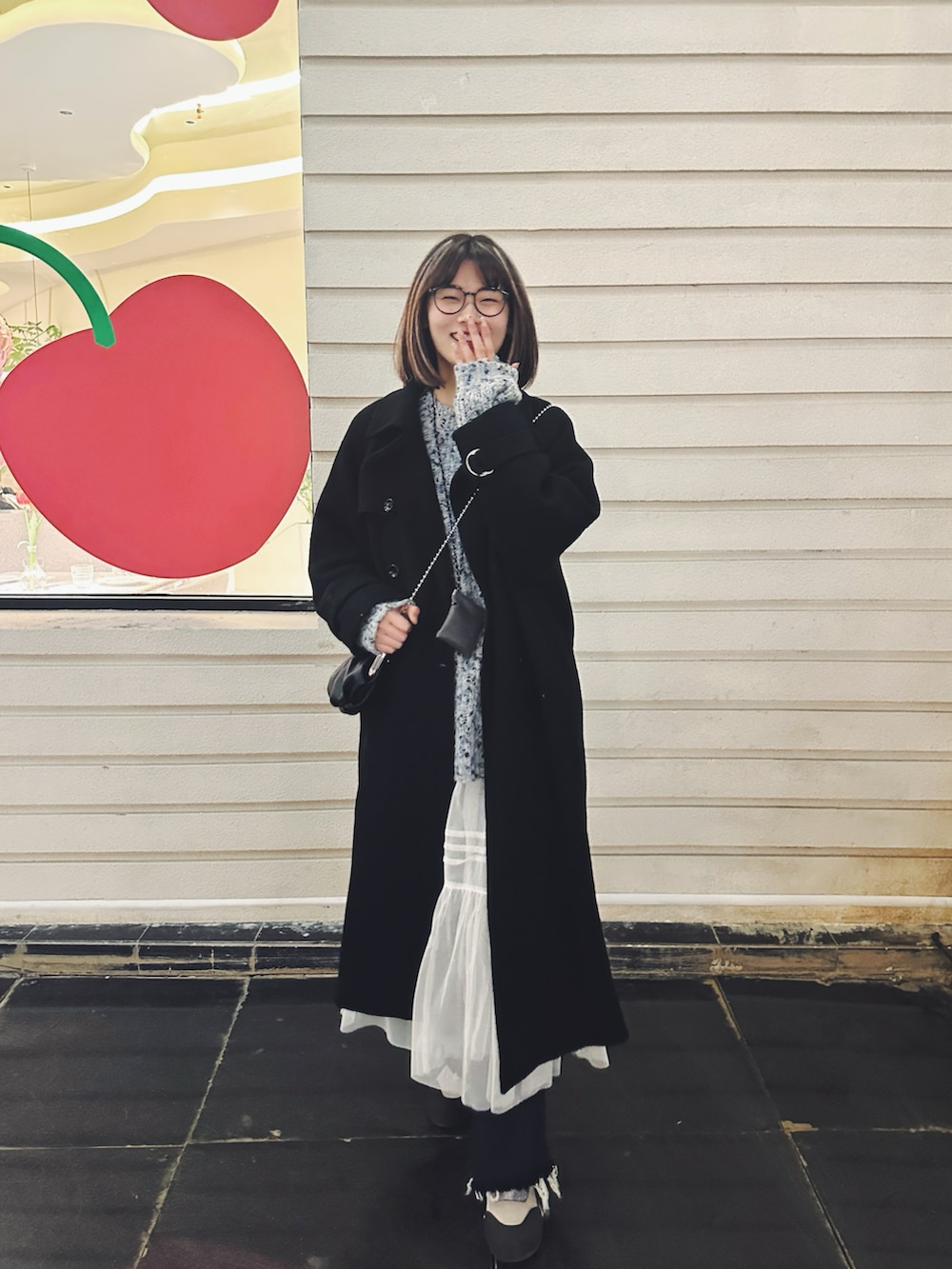 ブラック系のショルダーバッグ、ブラック系のチェスターコート、ホワイト系のワンピースを着用したレディースの春コーディネートの3枚目の写真