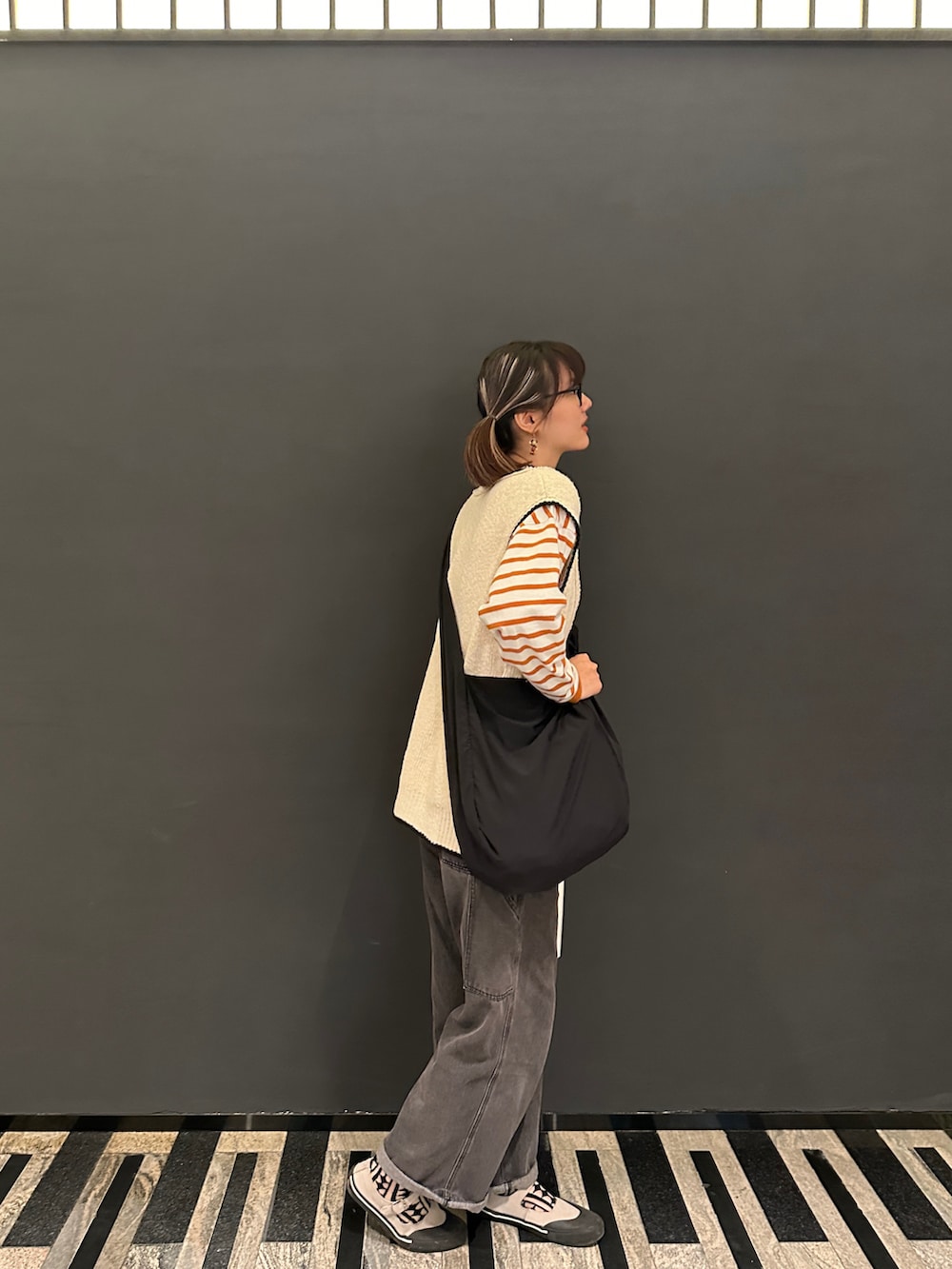 ホワイト系のベスト、オレンジ系のTシャツ/カットソー、ブラック系のショルダーバッグを着用したレディースの春コーディネートの2枚目の写真