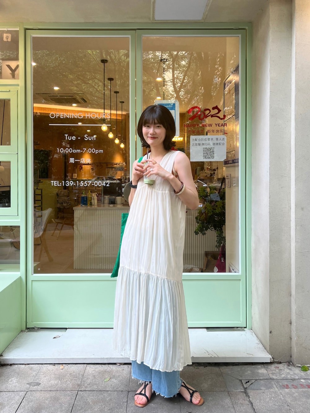 グリーン系のエコバッグ/サブバッグ、ホワイト系のワンピース、ブラック系のサンダルを着用したレディースの夏コーディネートの3枚目の写真