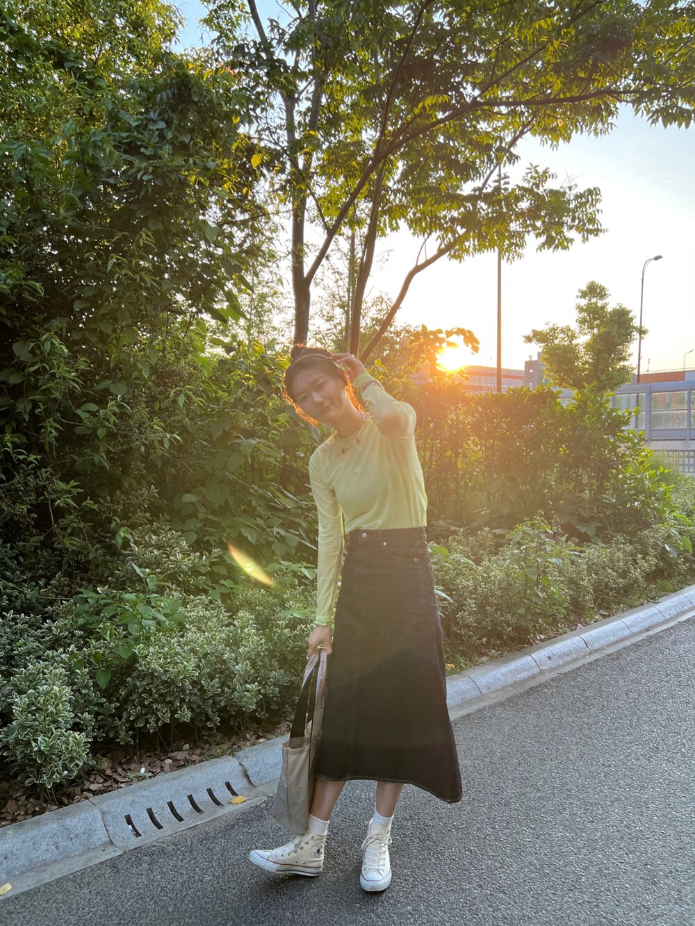 グリーン系のTシャツ/カットソー、ブルー系のデニムスカート、ホワイト系のスニーカーを着用したレディースの春コーディネートの2枚目の写真