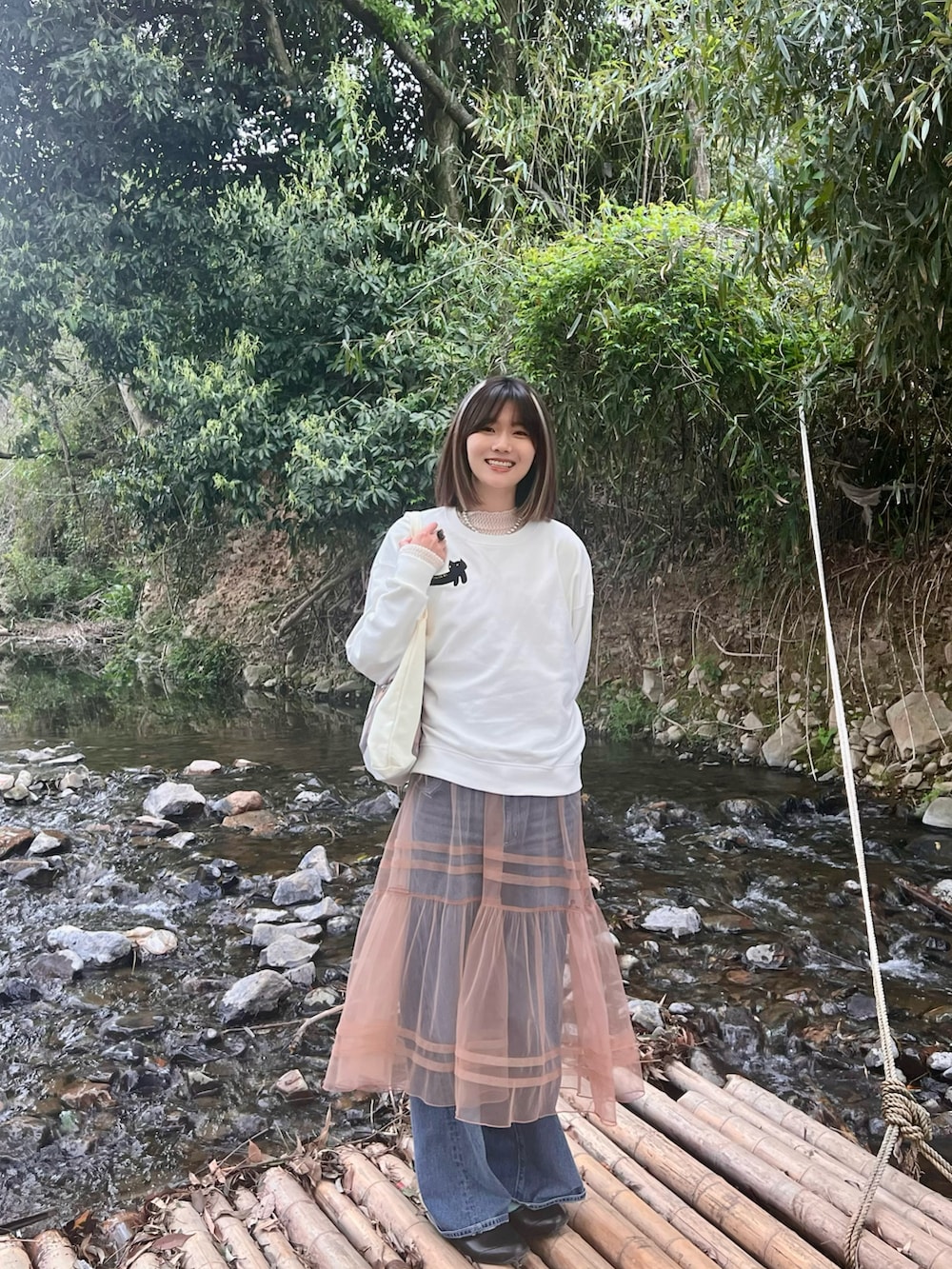 ベージュ系のワンピース、ブルー系のデニムパンツ、ホワイト系のその他トップスを着用したレディースの春コーディネートの2枚目の写真