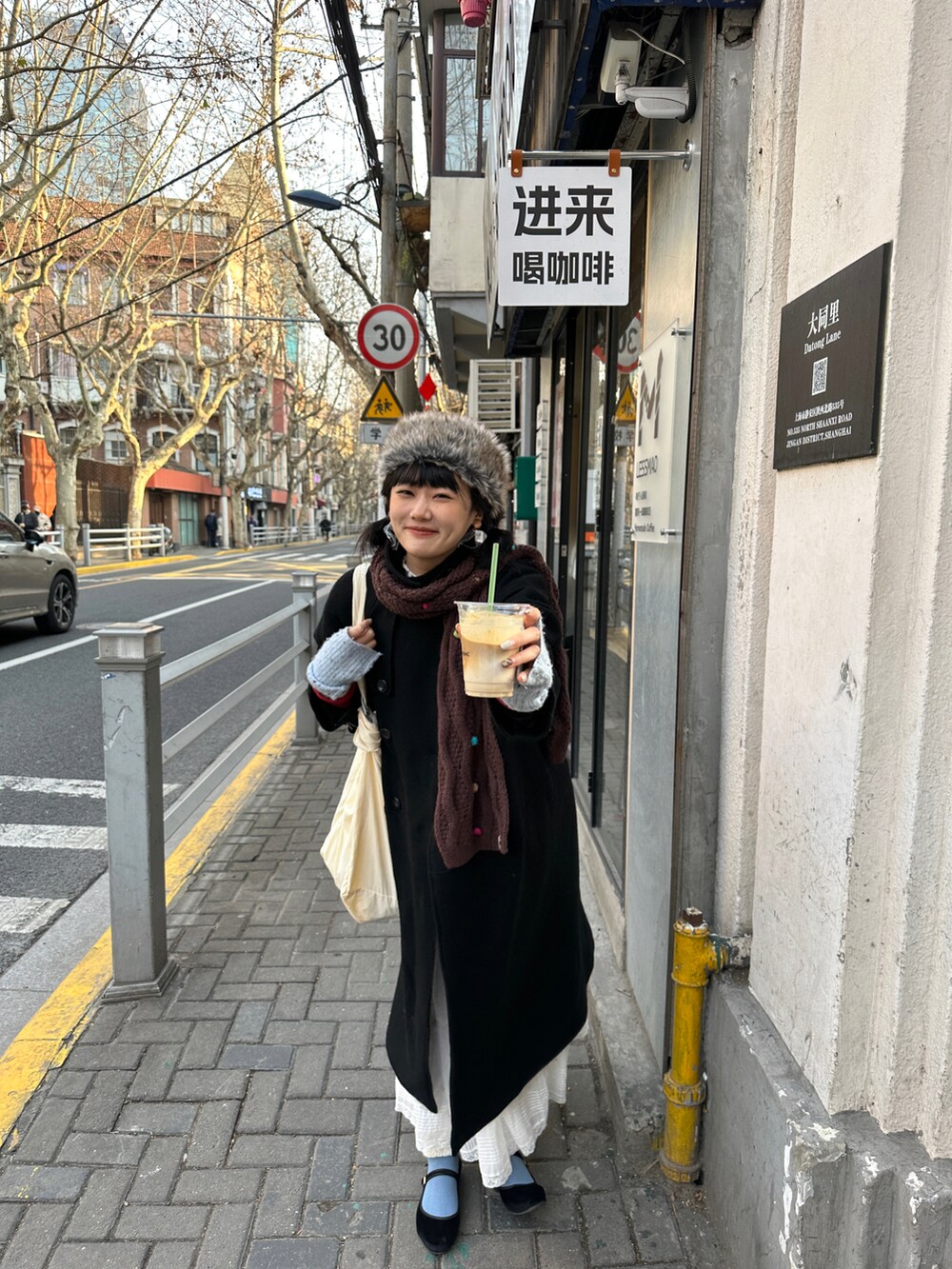 ブラック系のチェスターコート、ホワイト系のスカート、ホワイト系のショルダーバッグを着用したレディースの冬コーディネートの2枚目の写真