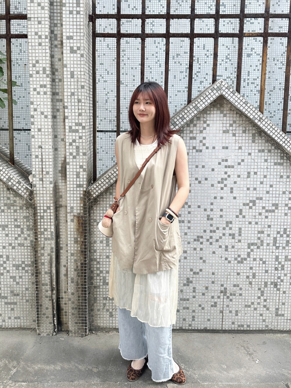 ベージュ系のベスト、ホワイト系のワンピース、ブルー系のデニムパンツを着用したレディースの秋コーディネートの3枚目の写真