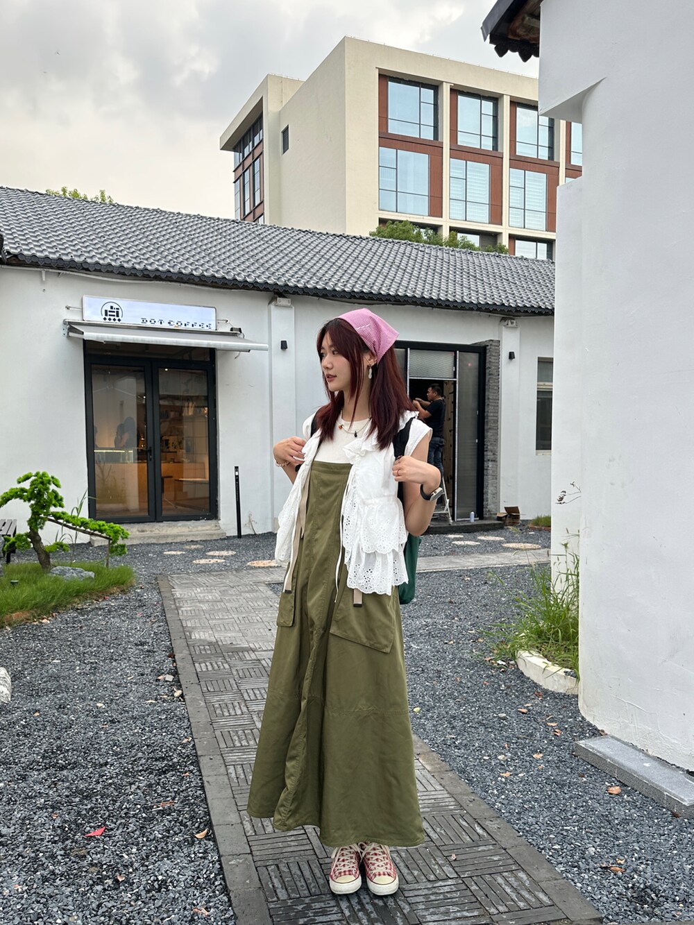 グリーン系のジャンパースカート、レッド系のスニーカー、ホワイト系のシャツ/ブラウスを着用したレディースの夏コーディネートの2枚目の写真