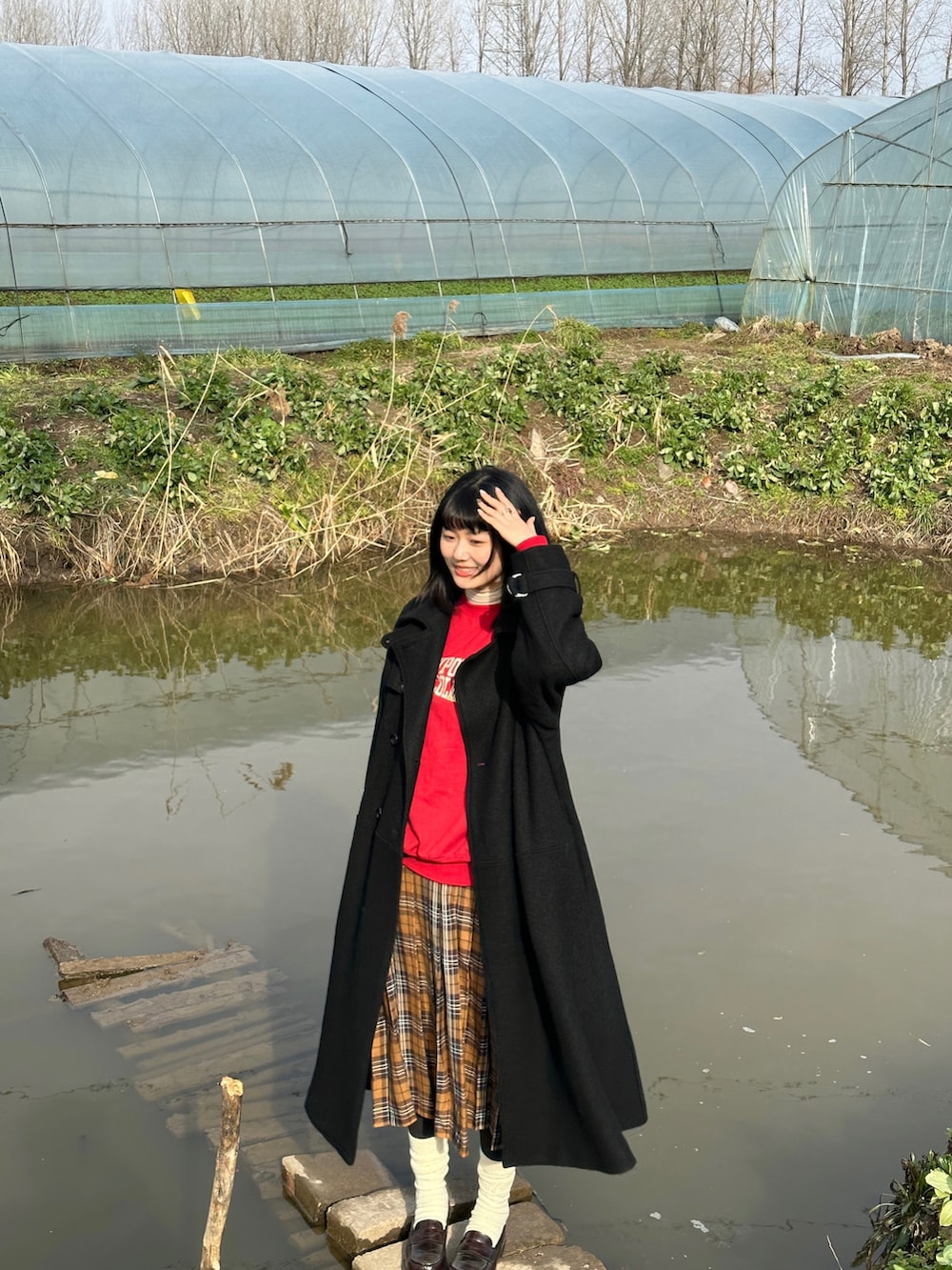 レッド系のスウェット、ブラック系のチェスターコート、ブラウン系のスカートを着用したレディースの冬コーディネートの3枚目の写真