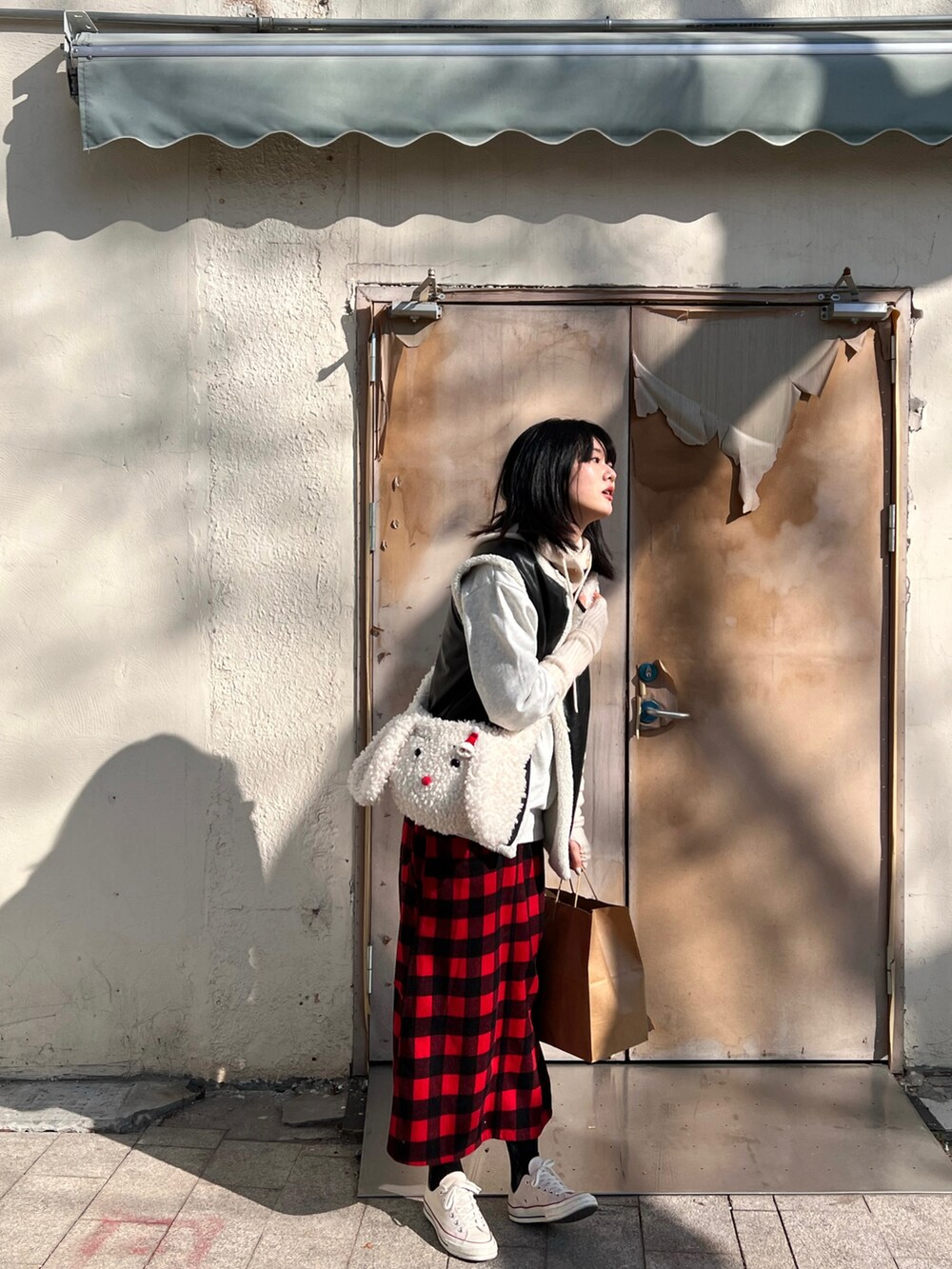 レッド系のスカート、ホワイト系のスニーカー、グレー系のスウェットを着用したレディースの冬コーディネートの2枚目の写真