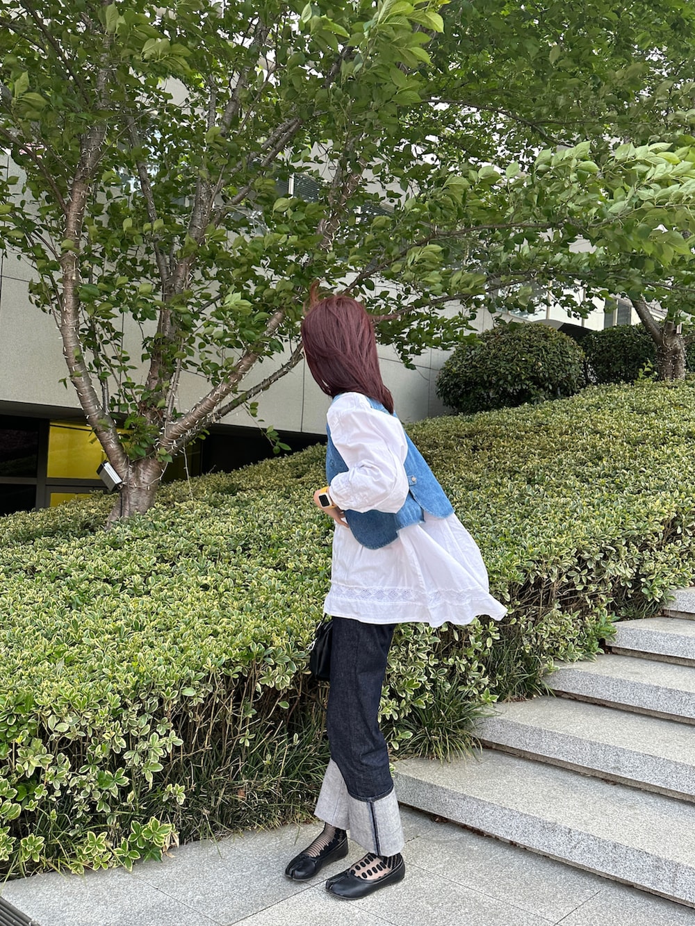 ブルー系のベスト、ホワイト系のシャツ/ブラウス、ブルー系のデニムパンツを着用したレディースの春コーディネートの2枚目の写真