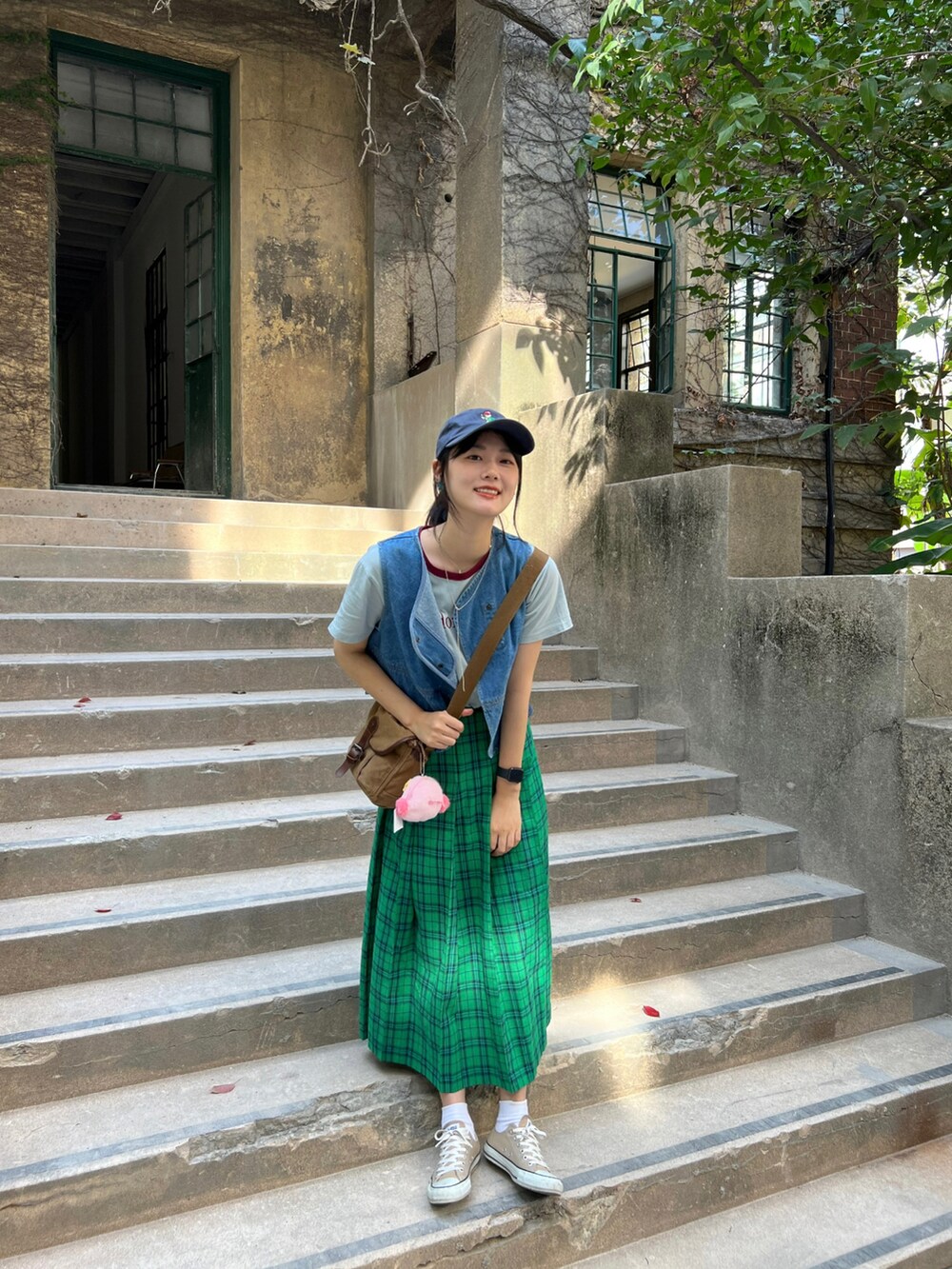 グリーン系のスカート、ベージュ系のスニーカー、ブルー系のベストを着用したレディースの秋コーディネートの3枚目の写真