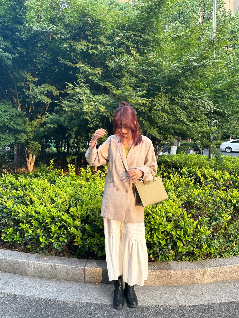 グレー系のテーラードジャケット、グリーン系のショルダーバッグ、ホワイト系のスカートを着用したレディースの春コーディネートの3枚目の写真