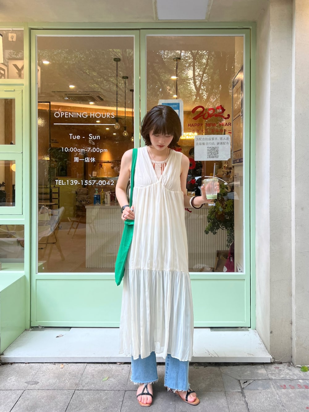 グリーン系のエコバッグ/サブバッグ、ホワイト系のワンピース、ブラック系のサンダルを着用したレディースの夏コーディネートの2枚目の写真