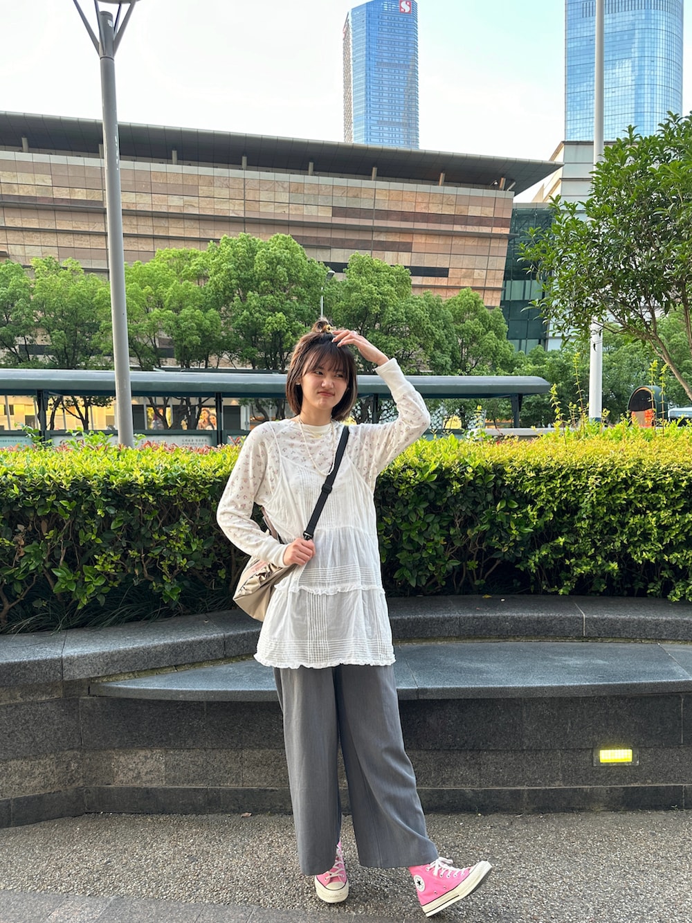 グレー系のその他パンツ、ピンク系のスニーカー、ベージュ系のショルダーバッグを着用したレディースの夏コーディネートの3枚目の写真