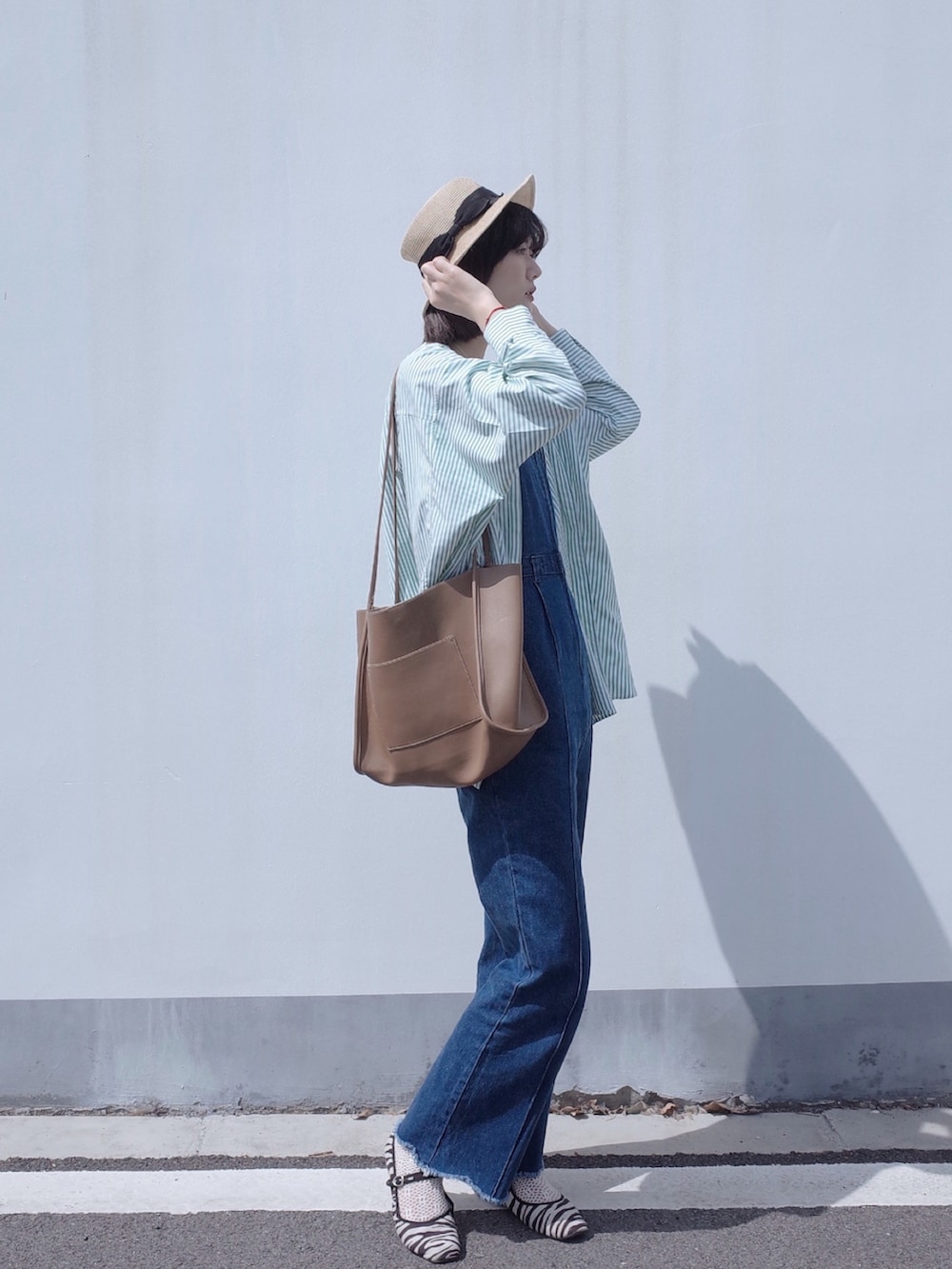 ブルー系のサロペット/オーバーオール、グリーン系のシャツ/ブラウス、イエロー系のトートバッグを着用したレディースの春コーディネートの2枚目の写真