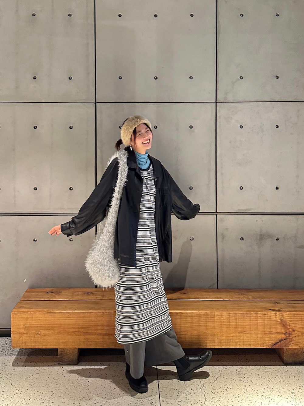 ホワイト系のハンドバッグ、ブラック系のブーツ、グリーン系のワンピースを着用したレディースの冬コーディネートの2枚目の写真